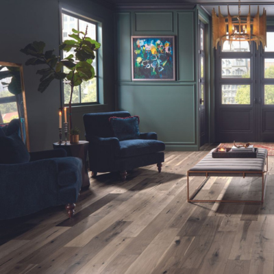 Light hardwood flooring installed in a modern living room, with dark green walls, and navy furniture.